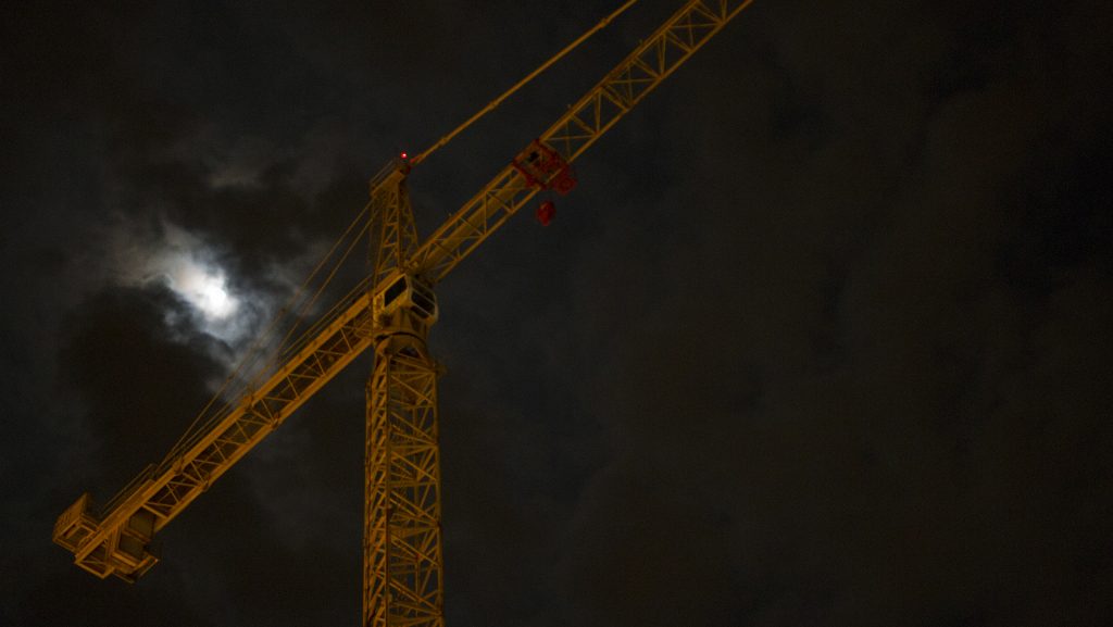 The moon is seen past a crane downtown early morning on Sunday, April 10, 2017. Saturday peaked with a near record 78 degree day which was the final night of Mission Creek music festival. (The Daily Iowan/Joseph Cress)