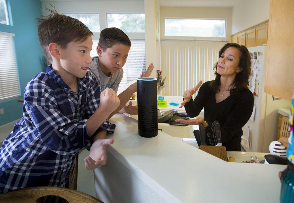 Eight-year-old Sutton Philips, left, his brother, 10-year-old Greyson Philips, center, and their mom, Liz Philips, right, play a game of rock-paper-scissors with "Alexa," their Amazon Echo wireless speaker and voice command personal assistant. (Howard Lipin/San Diego Union-Tribune/TNS)