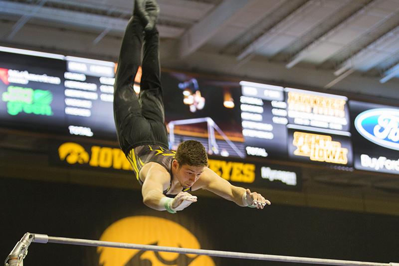 Rogelio Vazquez performs on the horizontal bars during mens gymnastics on Feb. 23, 2018. Vazquez earned a 12.200 for his performance. The Cornhusters defeated the Hawkeyes 402.8 to 398.5. (Katie Goodale/ The Daily Iowan)