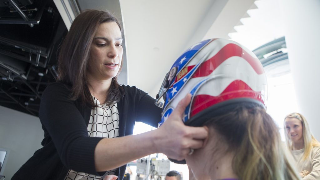 U.S. Olympian Jean Prahm helps a Stead Family Childrens Hospital patient try on her bobsled helmet during Prahms visit to the Stead Family Childrens Hospital on Tuesday, Feb. 13, 2018. Prahm was on the U.S. Olympic womens bobsled team from 1996-2006. (Lily Smith/The Daily Iowan)