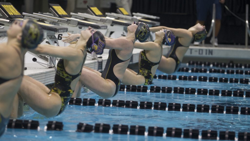 Swimmers dive into the pool for the Womens 50 yard backstroke during a swim meet between University of Iowa and Western Illinois on Friday, Feb. 2, 2018 at the University Aquatic Center. Swimmers competed in a variety of events including relays and freestyle swimming. (Katie Goodale/The Daily Iowan)