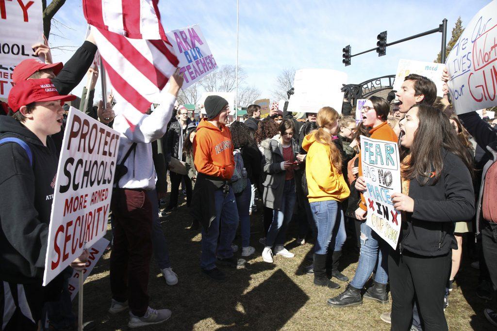 Students supporting gun-rights and the NRA, left, face off with student gun-control advocates, right, during a gathering of several hundred Barrington High School students at Memorial Park during the ENOUGH National School Walkout on Wed., March 14, 2018 in Barrington, Ill. (Stacey Wescott/Chicago Tribune/TNS)