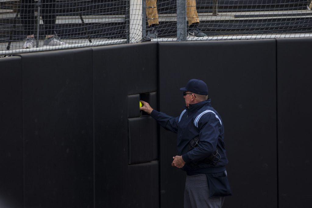 An umpire grabs a spare softball during the Iowa/Wisconsin softball game at Bob Pearl Field  on Sunday, April 8, 2018. The Hawkeyes defeated the Badgers in the third game of the series, 5-3. (Lily Smith/The Daily Iowan)