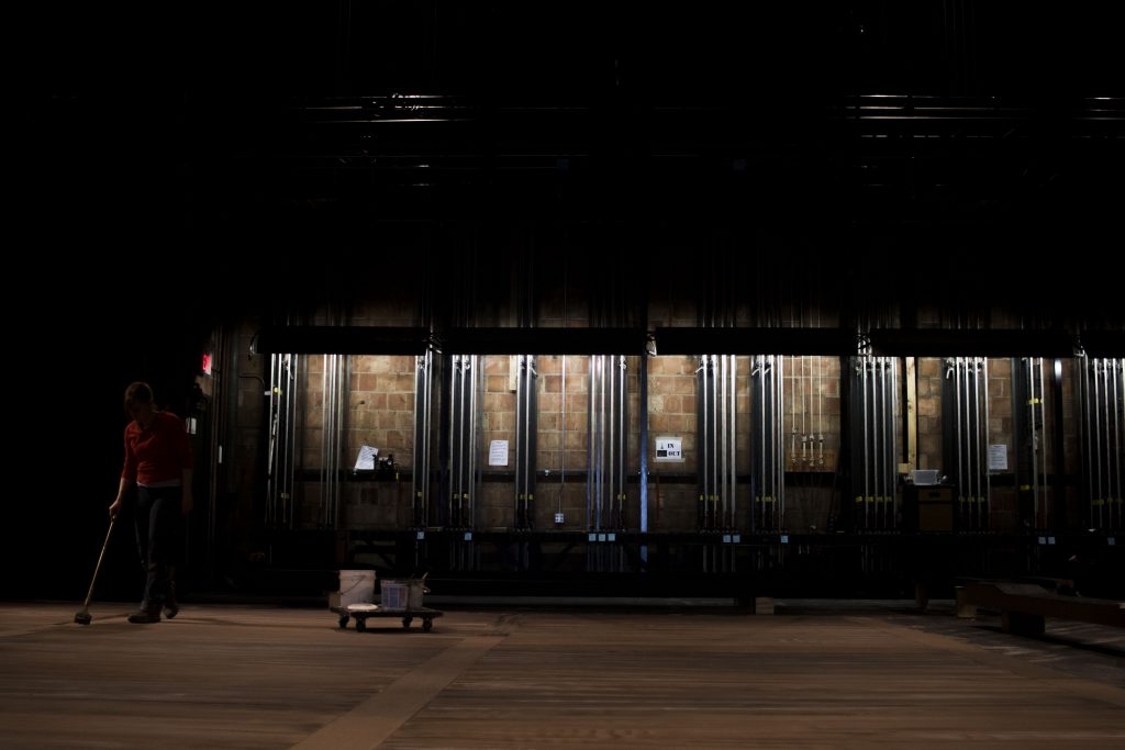 Scenic Charge Artist Kaitin Younger paints the floor of the E.C. Mabie Theatre to look like wood in the Theatre Building on Thursday, March 29, 2018.