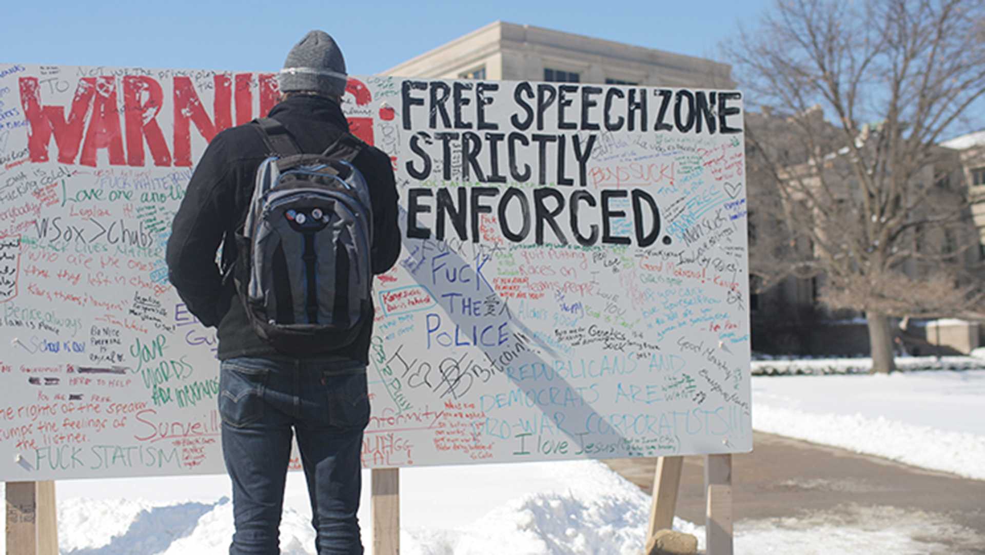 UI senior Spencer Smith writes on a board for the Freedom of Speech protest put on by Young Americans for Liberty group on the Pentacrest on Thursday, Feb. 26, 2015. The student run group allowed anyone to write whatever they wanted on the board. 