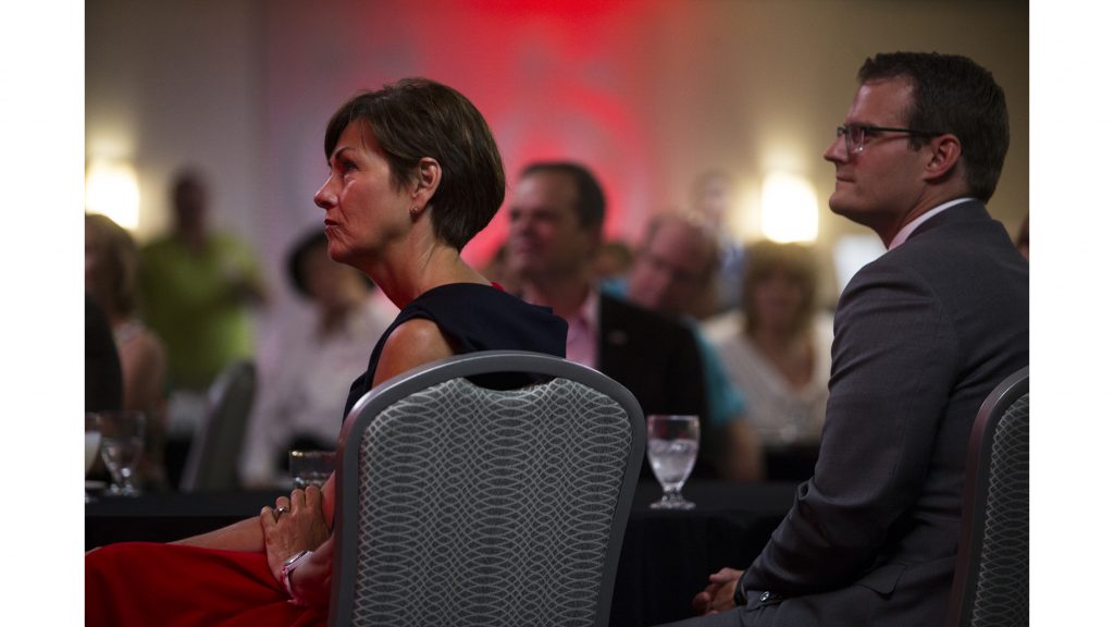 Iowa Gov. Kim Reynolds, left, listens to a speaker next to Iowa acting Lt. Gov. Adam Gregg during a Johnson County Republicans event in Coralville at the Radisson Hotel & Conference Center on Thursday, July 6, 2017. Iowa Gov. Reynolds spoke to Republican constituents who had a minimum donation of $25 per individual to attend, $125 to host, and $500 to sponsor. (Joseph Cress/The Daily Iowan)