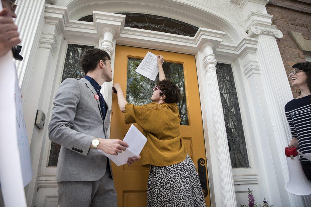 Meaghan Harding tapes a letter to the door of Bruce Harreld's home on May 4, 2018. UI's non-tenured faculty—grown to 52% since 2011—advocated for greater job security, fair pay, and benefits. (The Daily Iowan/Olivia Sun)