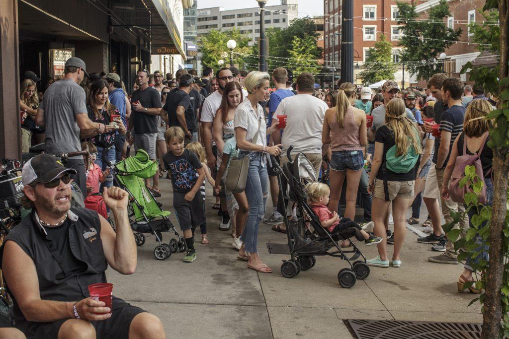 Partygoers walk and listen to music during the Iowa City Downtown District Block Party on Saturday June 23, 2018. The 2nd annual event during which open containers were allowed in a select portion of downtown attracted thousands of guests and featured a variety of activities and performances. (Nick Rohlman/The Daily Iowan)