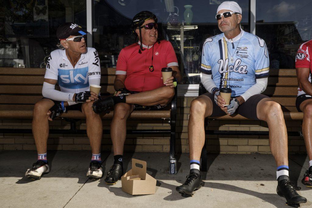 Tim James, Ron Cornelison and Dudley Rutherford of Loas Angelas California relax on benches in Kalona, Iowa during RAGBRAI on Friday, July 27, 2018. The three are part of a group that rides RAGBRI every other year. Riders rode from Sigourney to Iowa City on Day 6 of this years ride. (Nick Rohlman/The Daily Iowan)