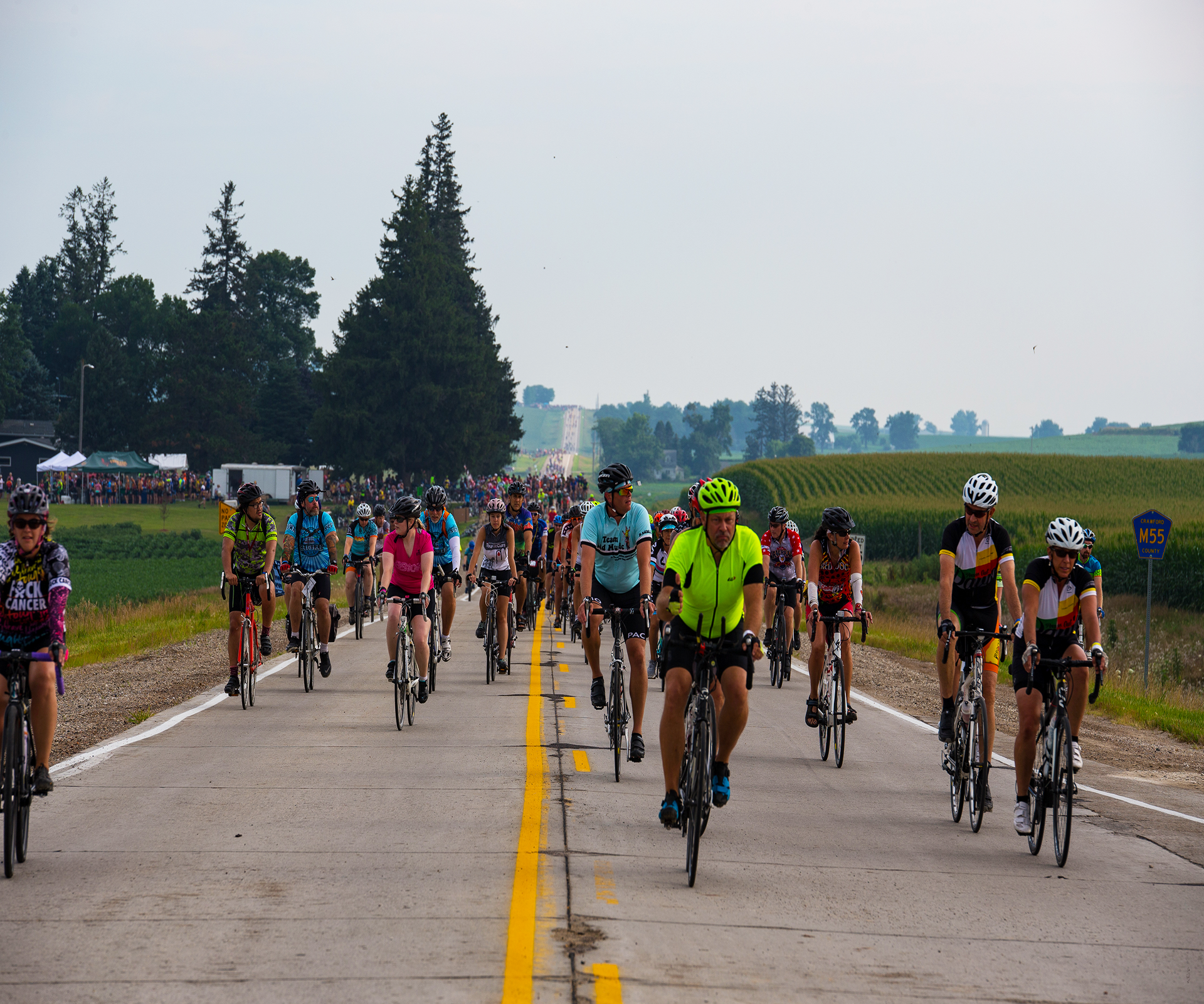 A large pack of RAGBRAI bikers pedal through the rural cornfields in Iowa on July 23. (Roman Slabach/The Daily Iowan)