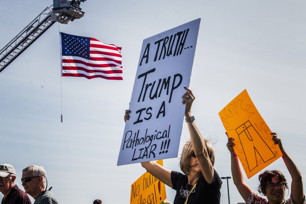 An attendee holds a sign near Northeast Iowa Community College in Peosta on July 26, 2018. Both pro- and anti-Trump demonstrators were present for the arrival of the president. (Katina Zentz/The Daily Iowan)
