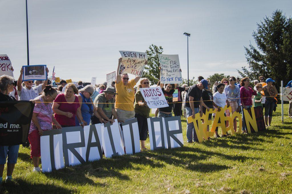 Attendees hold up signs outside of Northeast Iowa Community College in Peosta on July 26, 2018. Both pro- and anti-Trump demonstrators were present for the arrival of the president. (Katina Zentz/The Daily Iowan)