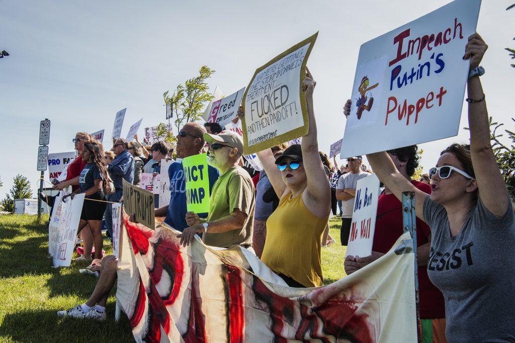 Attendees display posters outside of Northeast Iowa Community College in Peosta on July 26, 2018. Both pro- and anti-Trump demonstrators were present for the arrival of the president. (Katina Zentz/The Daily Iowan)