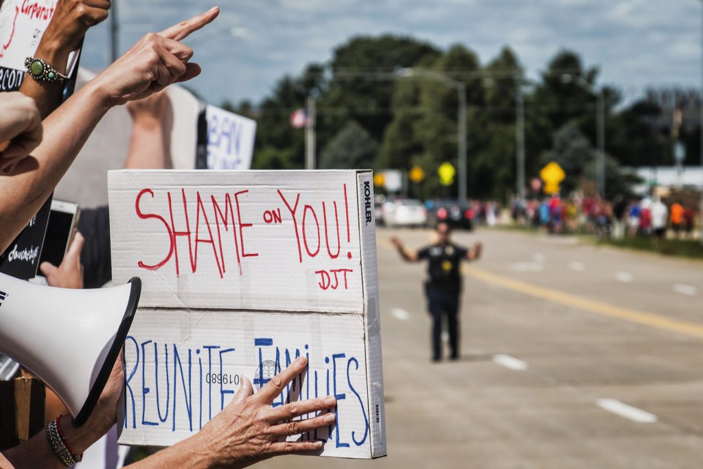 Attendees hold signs outside of Northeast Iowa Community College in Peosta on July 26, 2018. Both pro- and anti-Trump demonstrators were present for the arrival of the president. (Katina Zentz/The Daily Iowan)