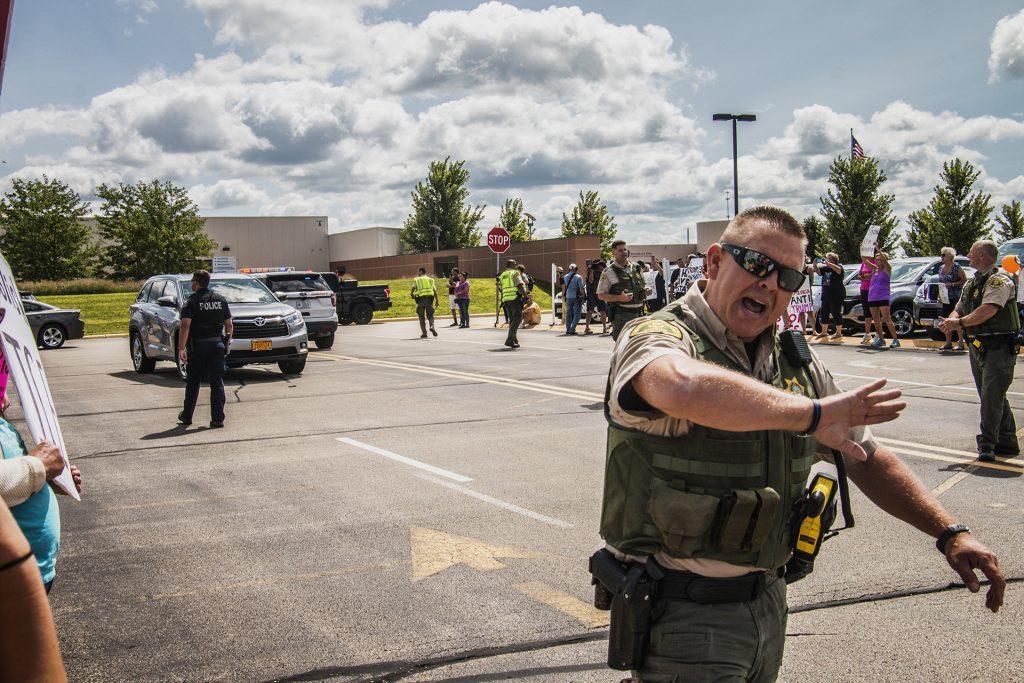 An officer pushes back the crowd outside of Northeast Iowa Community College in Peosta on July 26, 2018. Both pro- and anti-Trump demonstrators were present for the arrival of the president. (Katina Zentz/The Daily Iowan)
