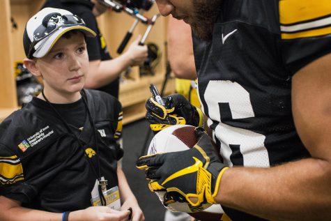 Kid Captain Garret Schuster watches his football get signed during Iowa Football Kids Day at Kinnick Stadium on Saturday, Aug. 11, 2018. 