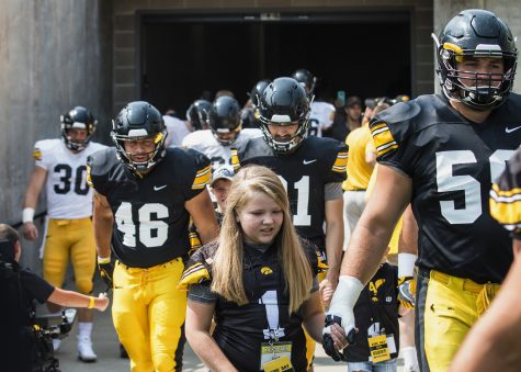 Kid Captain Livia Jackson walks with the football team during Iowa Football Kids Day at Kinnick Stadium on Saturday, Aug. 11, 2018. 