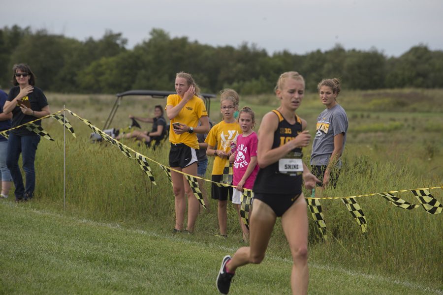 Bystanders look on as Senior Andrea Shine runs through the finish line during the Hawkeye Invitational at Ashton Cross Country course on Friday, Aug. 31, 2018. 
