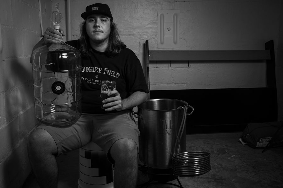 Luke Burnett, a UI senior, poses for a portrait with some brewing equipment in his home on Thursday, Aug. 30, 2018. Burnett has been brewing beer since February 2018. Each beer takes approximately five weeks from start to finish, and has to go through a rigorous process of heating, cooling, fermentation, and finally bottling. I love beer and I like doing stuff myself, so why not make my own beer that I like to drink, Burnett said.
