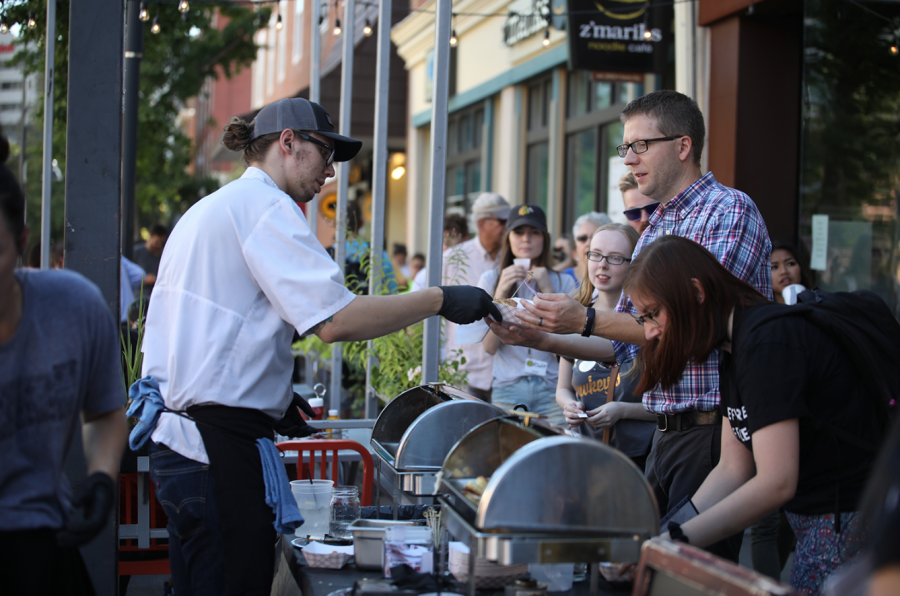 A Pullman Bar and Diner worker is seen serving food to a customer during Taste of Iowa City on Aug. 23, 2017. Taste of Iowa City is an event where downtown restaurants serve food on the streets. 