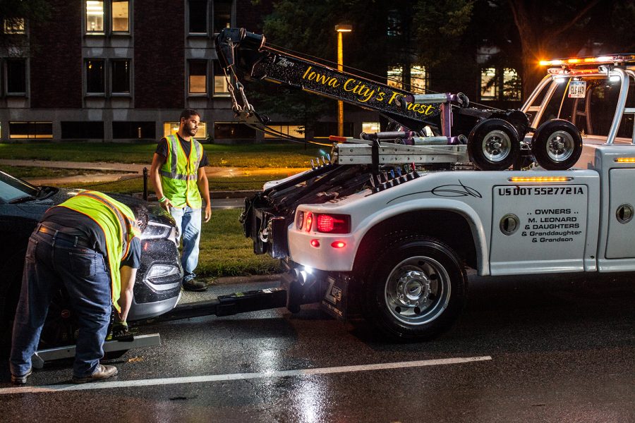 Towing company employees assist stalled motorists after heavy rains caused Iowa Avenue to briefly flood near the Iowa River on Tuesday, Aug. 28, 2018.