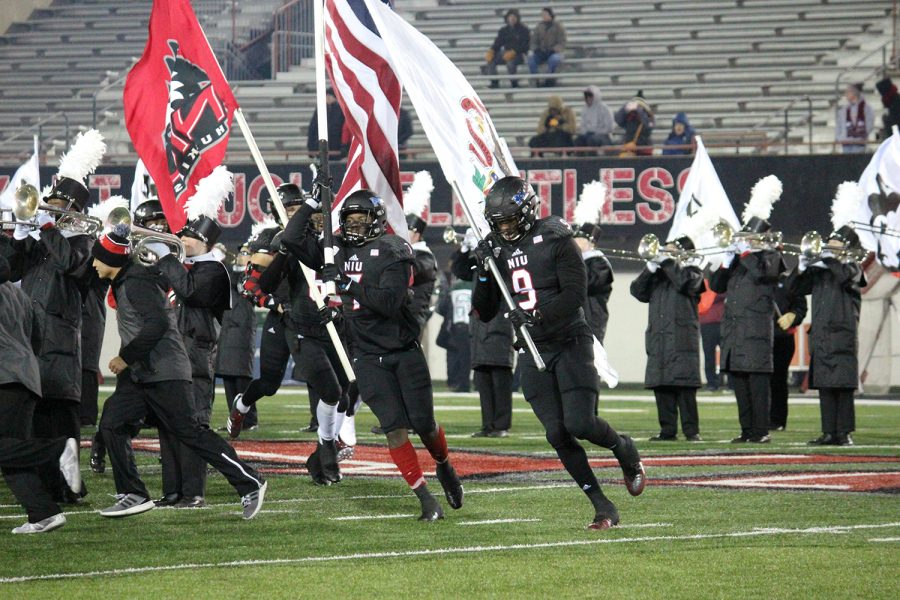 Northern Illinois football players run out on to the field before a game.