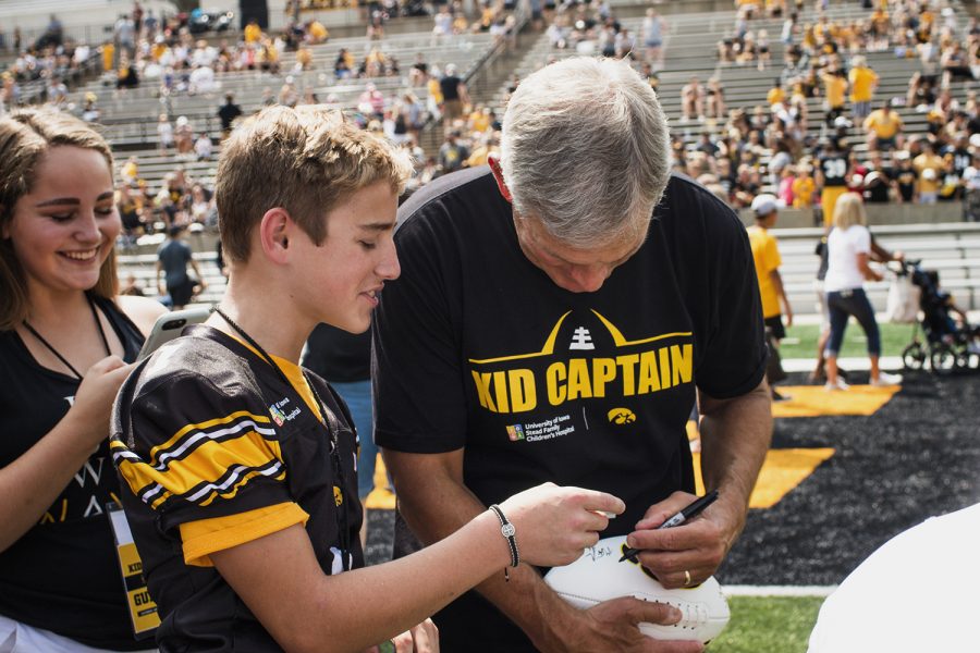 Kid Captain Christopher Turnis (left) watches Iowa head coach Kirk Ferentz (right) sign his football during Iowa Football Kid's Day at Kinnick Stadium on Saturday, August 11, 2018. The 2018 Kid Captains met the Iowa football team and participated in a behind-the-scenes tour of Kinnick Stadium. Each child's story will be featured throughout the 2018 Iowa football season. (Katina Zentz/The Daily Iowan)