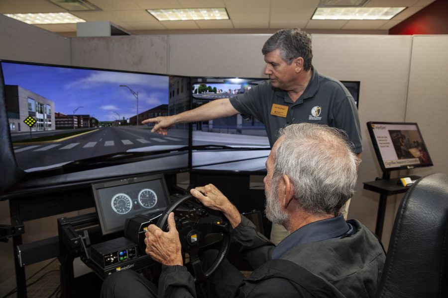 Joe+Meidlinger+instructs+Tom+Beaver+of+Iowa+City+on+the+use+of+a+mini+sim+driving+simulator+during+an+open+house+at+the+National+Advanced+Driving+Simulator+in+Coralville+on+Wednesday+Oct.+10%2C+2018.+Meidlinger+is+the+program+supervisor+for+the+mini+sim+program.+Beavers+son%2C+Greg%2C+a+UI+senior+and+mechanical+engineering+student%2C+works+in+the+mini+sim+program.+