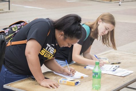 Students fill paperwork on the T. Anne Cleary Walkway on Tuesday, September 26, 2017. UISG hosted tables where students could register to vote. 