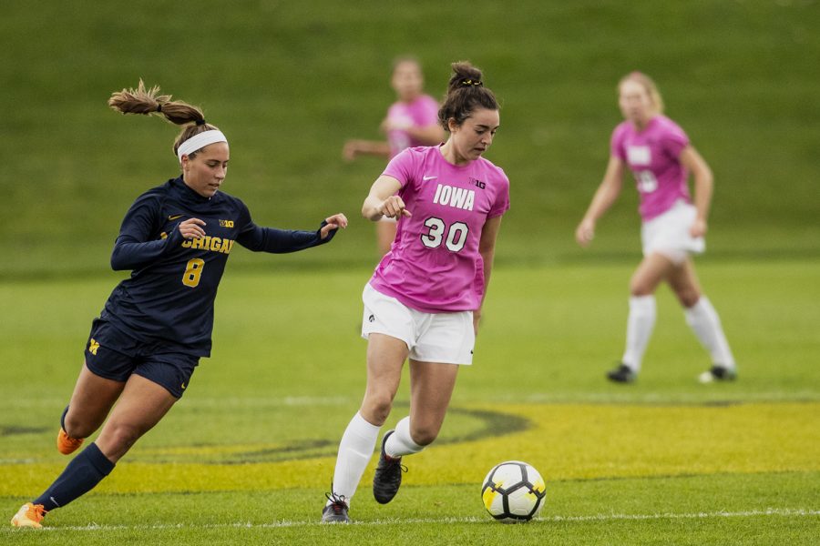 Iowa forward Devin Burns (30) dribbles past Michigan midfielder Sarah Stratigakis during Iowa’s game against Michigan at the Hawkeye Soccer Complex on Sunday Oct. 14, 2018. The Hawkeyes defeated the Wolverines 1-0. (Nick Rohlman/The Daily Iowan)