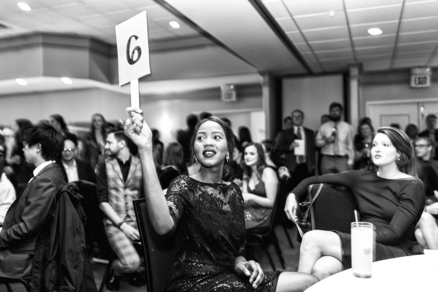 Aurora Arap, a first year law student at the University of Iowa College of Law raises her paddle to make a bid during the live auction at the law school’s annual fundraiser for the Equal Justice Foundation at the Universtiy Club on Friday, Oct. 26, 2018. EJF provides grans for law students to do public interest internships during the summer months. In 2017, the auction raised almost $9,000.