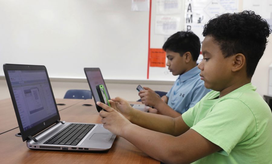 Sixth graders Hemant Pacha, left, 11, and Mikey Shands, 11, work on their phones and computers during a computer coding club gathering at Barbara Bush Middle School in Irving, Texas on Thursday, January 11, 2018. They both create an app for games and Mikey has his own YouTube channel. Hemant wants to be a doctor and a part-time video game designer and Mikey wants to be a cartoon animator. (David Woo/Dallas Morning News/TNS)