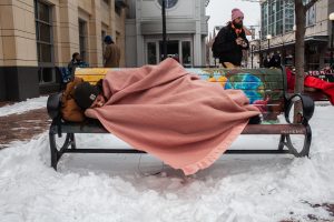 Demonstrators lay on benches during a Sleep In demonstration in the Pedestrian Mall in Iowa City on Monday, January 14, 2019. The benches have been in the works since 2014, but were installed in November of 2018. (Wyatt Dlouhy/The Daily Iowan)