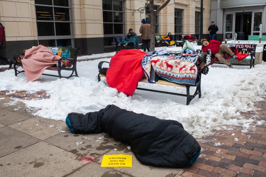 Demonstrators lay on benches during a "Sleep In" demonstration in the Pedestrian Mall in Iowa City on Monday, January 14, 2019. The benches have been in the works since 2014, but were installed in November of 2018. (Wyatt Dlouhy/The Daily Iowan)