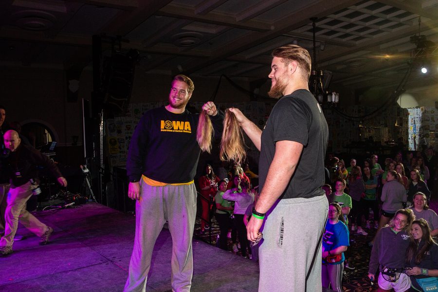 Landon (left) and Levi Paulson (right) hold up their hair during Dance Marathon 25 at the Iowa Memorial Union on Saturday, Feb. 2, 2019. After Landons girlfriend Alexis Henry raised over $10,000 for the Big Event, the twins committed to losing their locks.