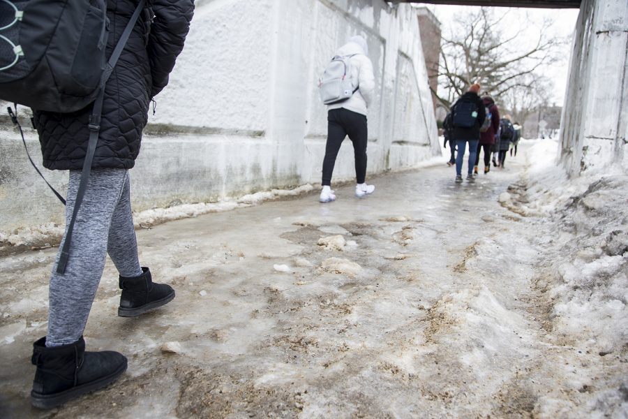 Students walk across a sheet of ice in Iowa City on Monday, February 25, 2019. Ice froze over pavements after the rainy weekend, but Iowa City is running out of salt to clear sidewalks.