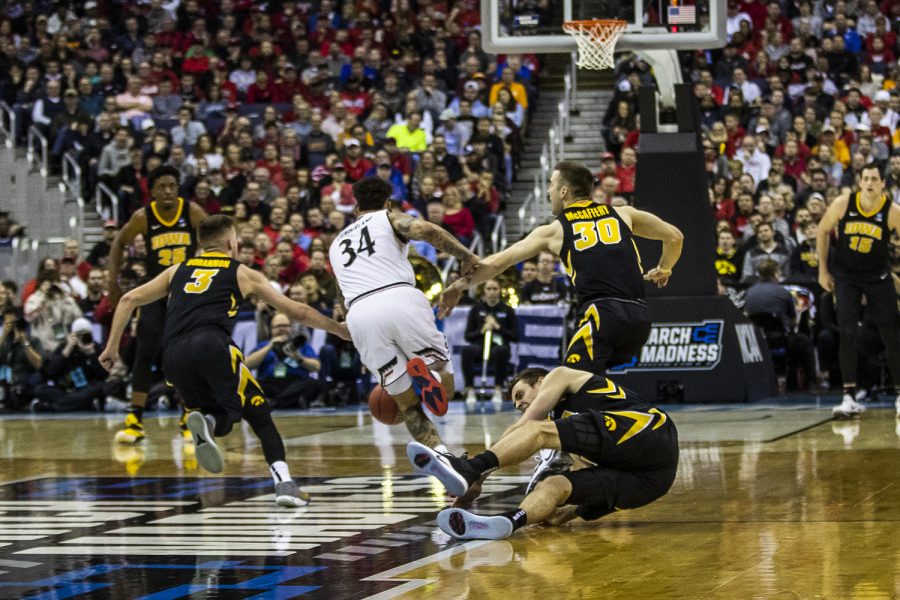 Iowa forward Nicholas Baer falls to the ground after Cincinnati guard Jarron Cumberland drives past during the NCAA game against Cincinnati at Nationwide Arena on Friday, March 22, 2019. The Hawkeyes defeated the Bearcats 79-72.