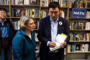 Democratic presidential hopeful Andrew Yang signs an attendee’s copy of his book The War on Normal People following a campaign event at Prairie Lights on Wednesday.