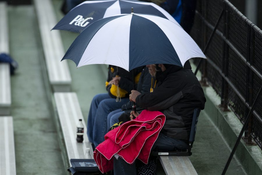 Fans hide under an umbrella as it starts to rain during a game between Iowa and Illinois. The Hawkeyes defeated the Illini 8-4 at Duane Banks Field on Mar 29, 2019. 