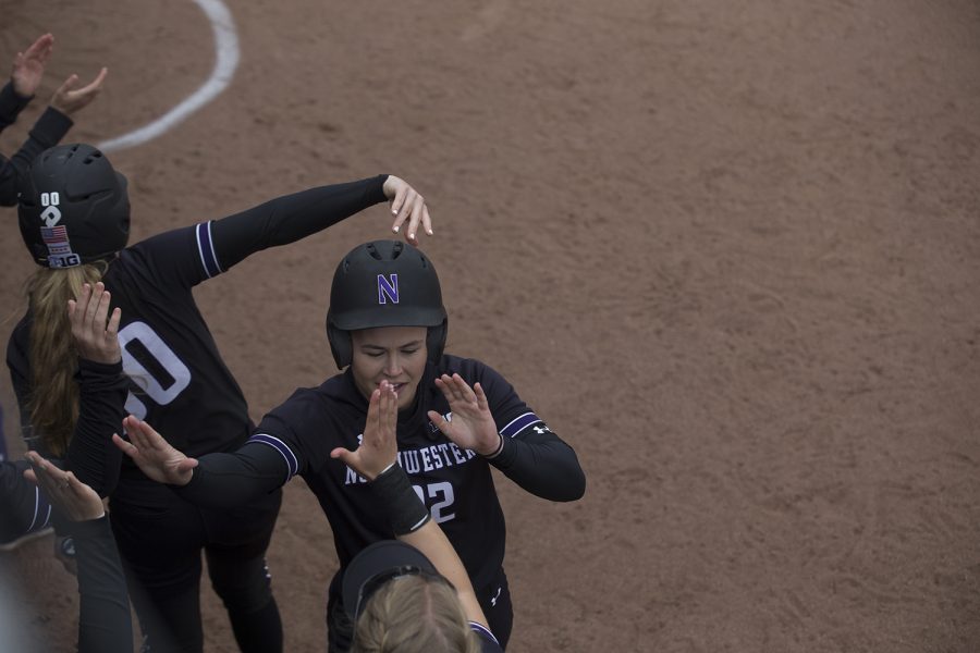 Northwestern outfielder Emma Bartz high fives her teammates after scoring the first run of the game during the second inning of the conference opening softball game at Pearl Field on Friday, March 29, 2019. The Wildcats defeated the Hawkeyes 5-1. 