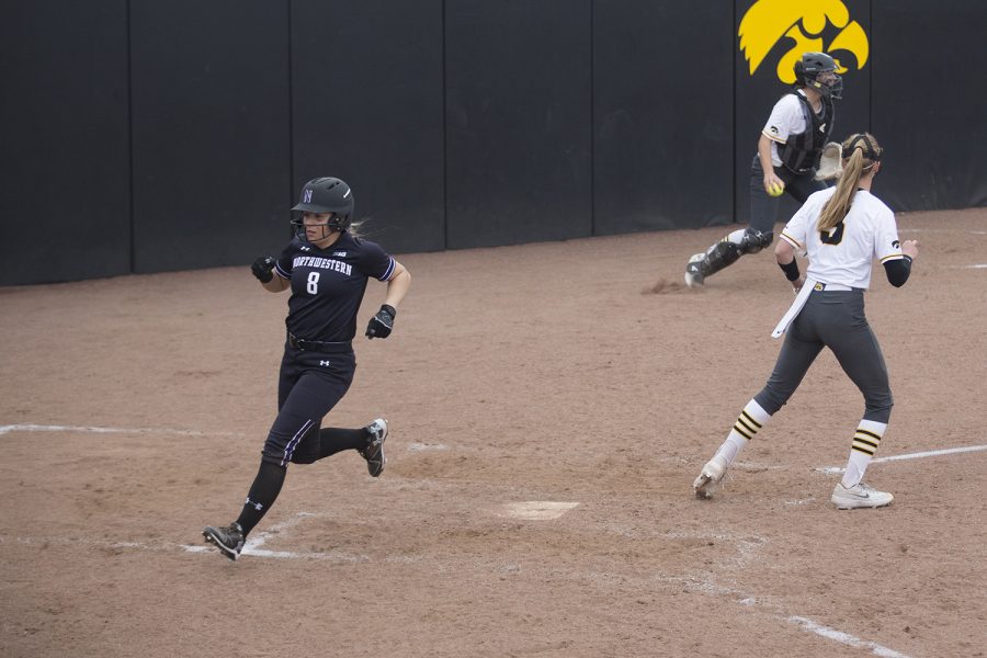 Norhtwestern infielder Skyler Shellmyer runs through home plate, scoring one of four runs during the seventh inning of the conference opening softball game at Pearl Field on Friday, March 29, 2019. The Wildcats defeated the Hawkeyes 5-1. 