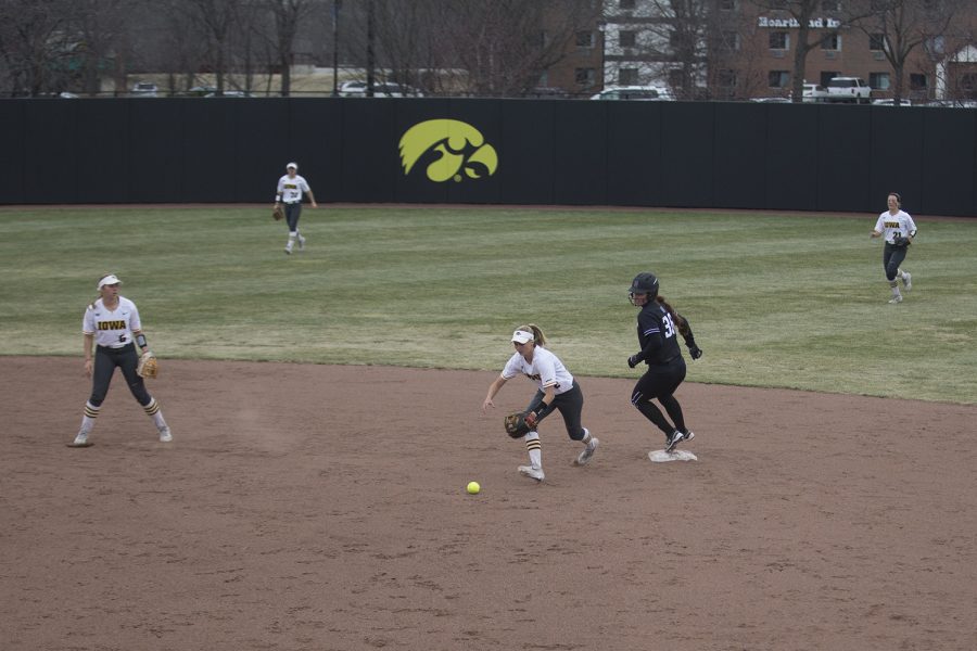 Iowa utility player Aralee Bogar scrambles to pick up a dropped ball during the seventh inning of the conference opening softball game at Pearl Field on Friday, March 29, 2019. The Hawkeyes let the four runs get by them during the seventh inning. The Wildcats defeated the Hawkeyes 5-1. 