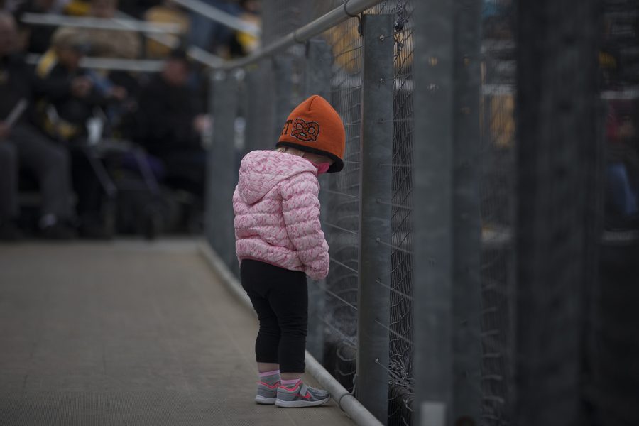 A young fan looks down at the field during the conference opening softball game at Pearl Field on Friday, March 29, 2019. The Wildcats defeated the Hawkeyes 5-1. 