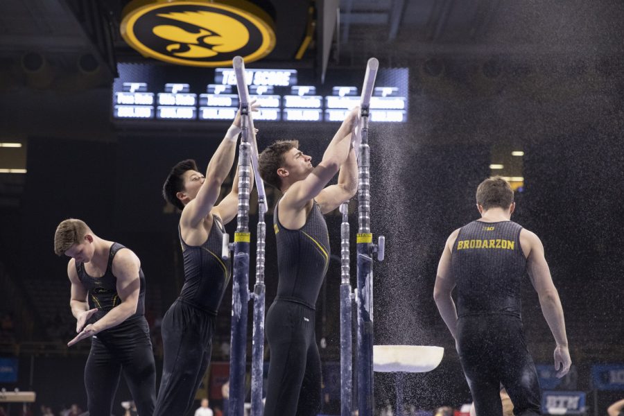 Hawkeye gymnasts chalk up the parallel bars Friday in Carver Hawkeye Arena during the Men's Big Ten Championships. Penn State won the team competition with a combined score of 410.350 points. 