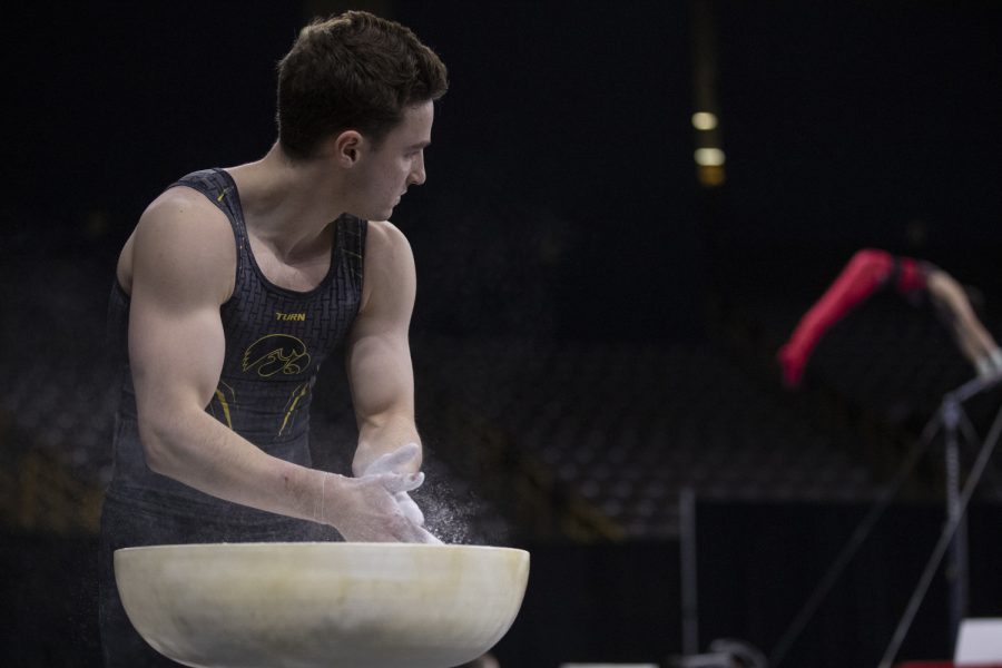 Hawkeye gymnast Jake Brodarzon watches an opposing gymnast compete as he prepares for the parallel bars Friday in Carver Hawkeye Arena during the Men's Big Ten Championships. Penn State won the team competition with a combined score of 410.350 points. 