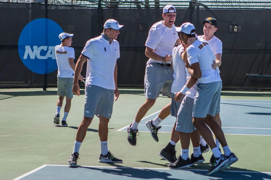 Iowa players huddle to celebrate Will Davies' win during a men's tennis match between Iowa and Michigan at the HTRC on Sunday, April 21, 2019. The Hawkeyes, celebrating senior day, defeated the Wolverines, 4-1.