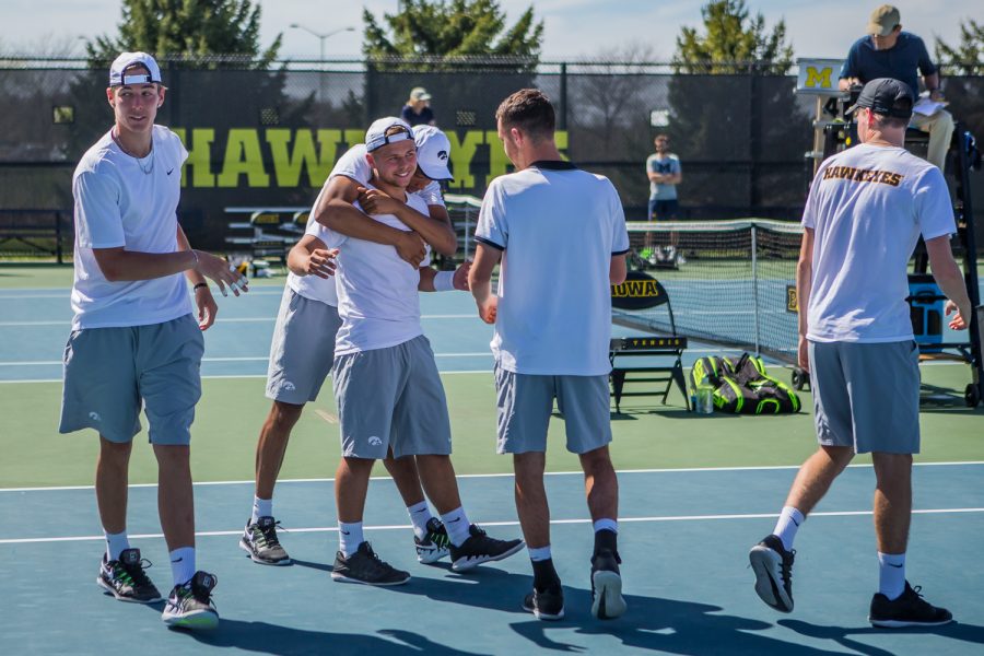 Iowa players huddle around Will Davies after his win during a men's tennis match between Iowa and Michigan at the HTRC on Sunday, April 21, 2019. The Hawkeyes, celebrating senior day, defeated the Wolverines, 4-1.