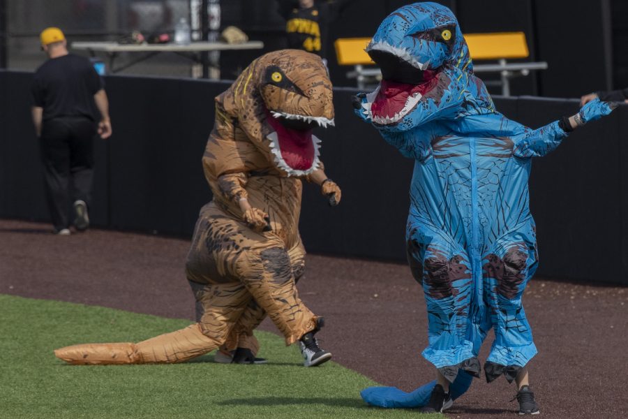 Two fans recover take a breather after running a race in dinosaur costumes between innings during the afternoon Iowa vs Rutgers game at Duane Banks Field on Saturday, April 7, 2019. The Hawkeyes defeated the Scarlet Knights 9-5. 