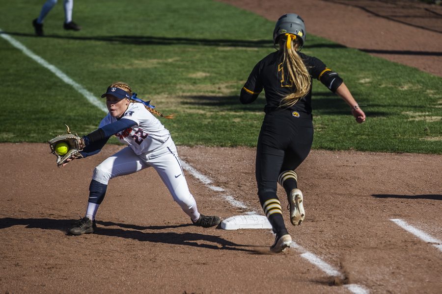 Illinois utility player Avrey Steiner catches the ball as Iowa infielder Cameron Cecil runs to first during the game against Illinois at the Bob Pearl Softball Field on Saturday, April 13, 2019. The Hawkeyes defeated the Fighting Illini 4-3.