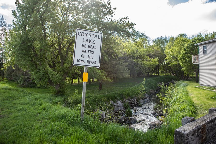 Above a sign marks the headwaters of the Iowa River on May 20, 2019. The stream below the sign runs through Crystal Lake, Iowa before traveling northeast, where it becomes traversable. 